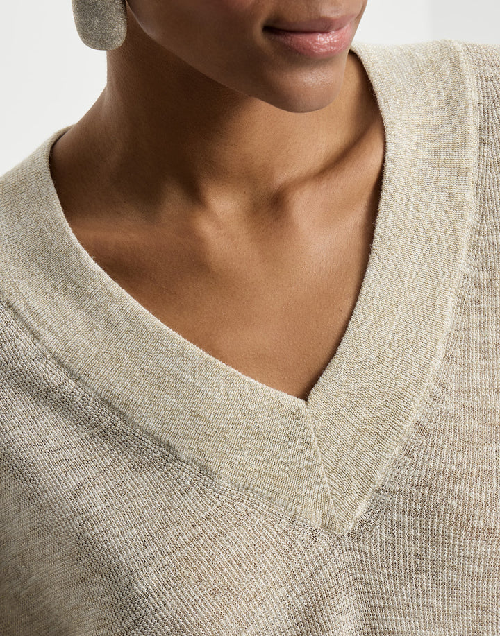 Close-up of a person wearing a beige sweater with a V-neck