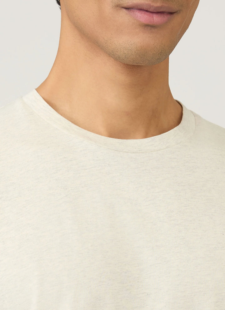 Close-up of a person wearing a plain white t-shirt against a neutral background