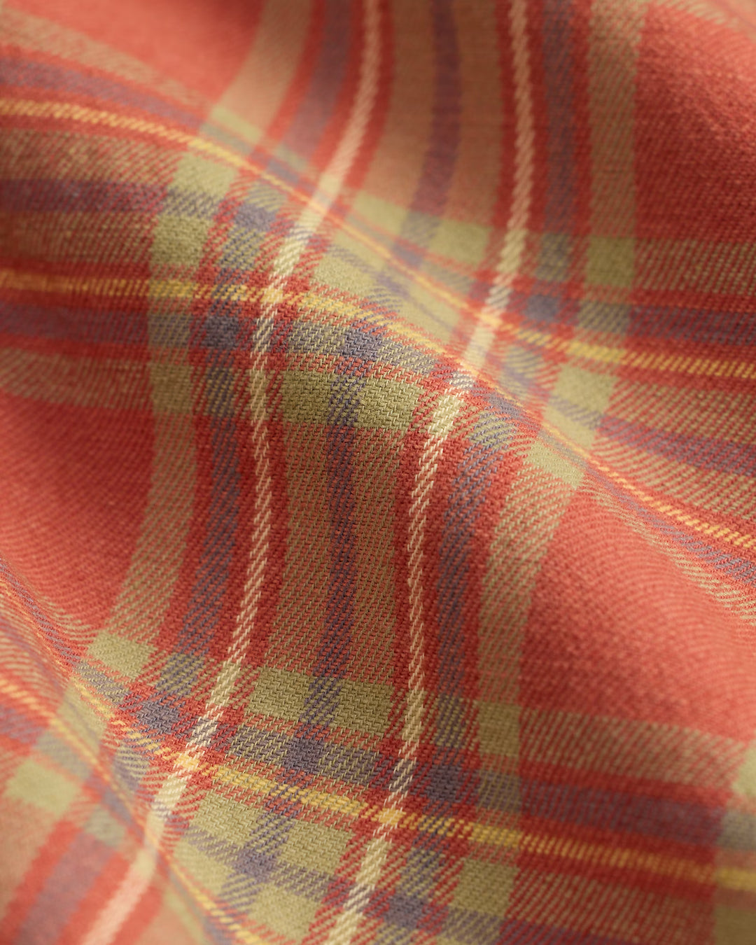 Close-up of a plaid fabric with red, yellow, and blue colors.