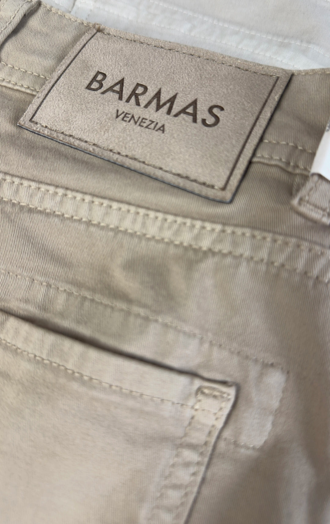 Close-up of beige pants with a Barmas Venezia label.