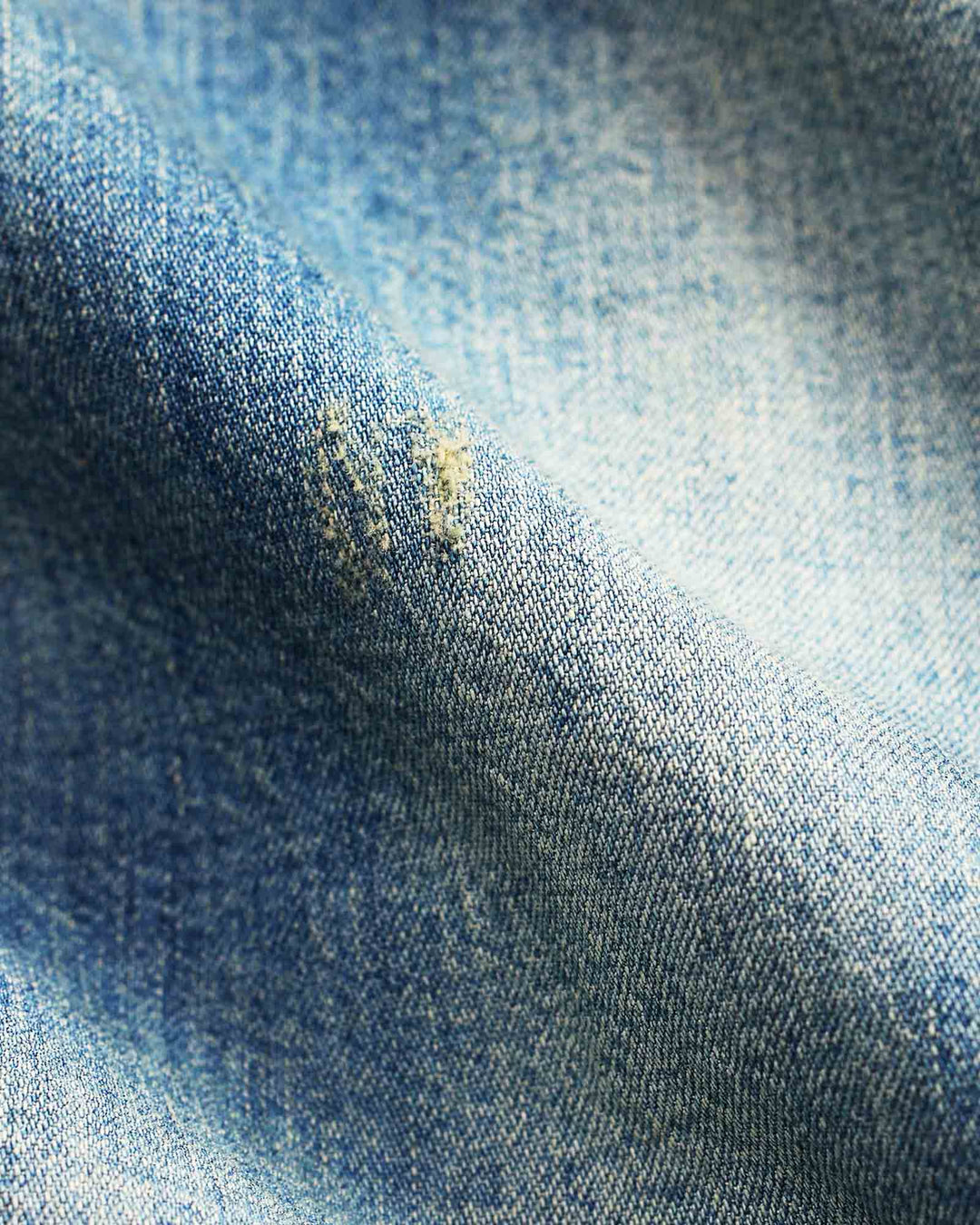 Close-up of blue denim fabric with a stain.