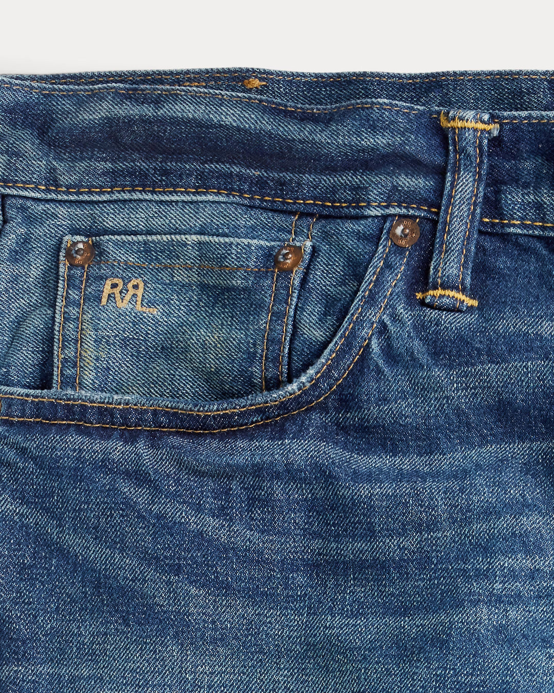 Close-up of blue denim jeans with a brand logo on the pocket.