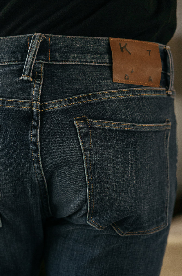 Close-up of blue jeans with a brown leather patch on the back pocket.