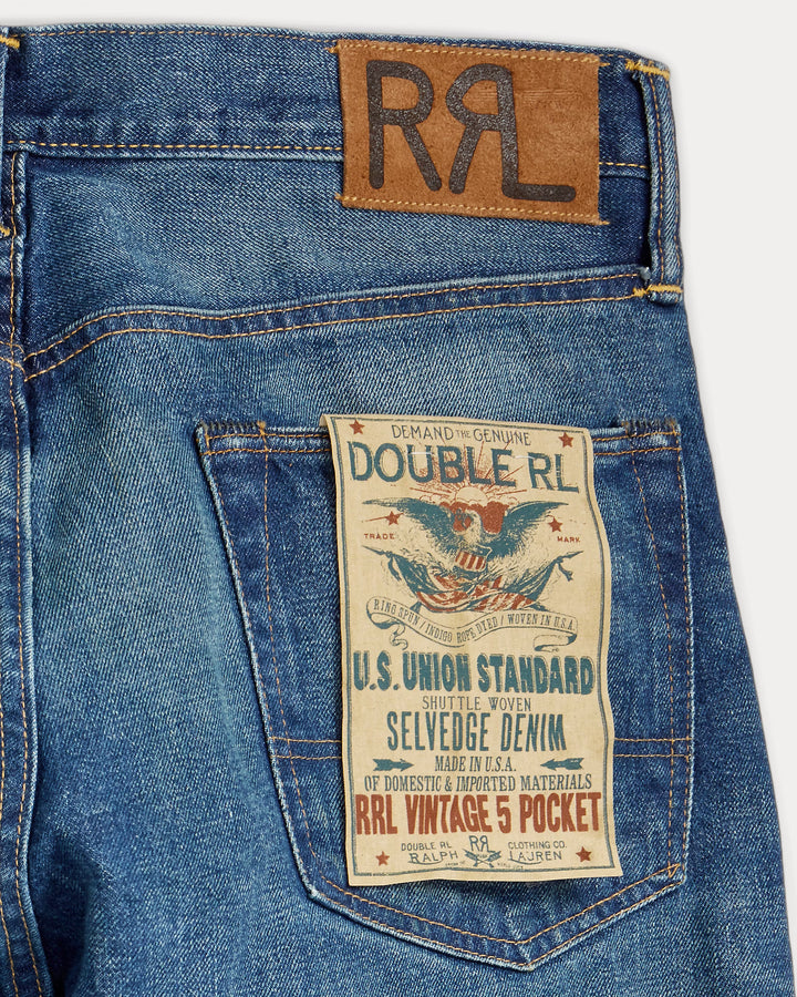 Close-up of blue jeans with a Double RL label and back pocket label on a white background