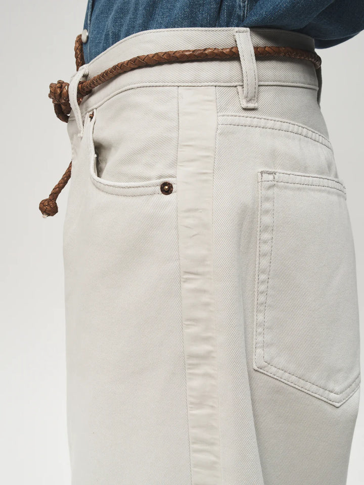 Close-up of light-colored jeans with a brown belt on a white background