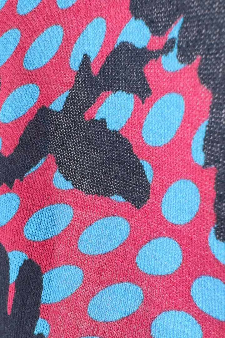 Close-up of socks with black abstract designs on a red and blue polka dot pattern.