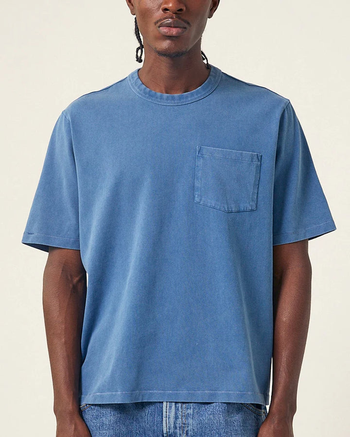 Man wearing a blue t-shirt with a pocket on a beige background