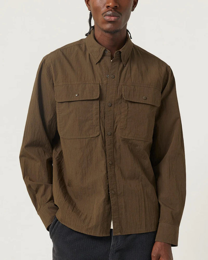 Man wearing a brown shirt with two front pockets on a white background