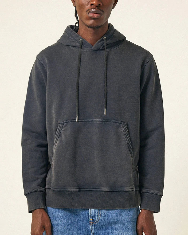 Person wearing a dark gray hoodie on a beige background