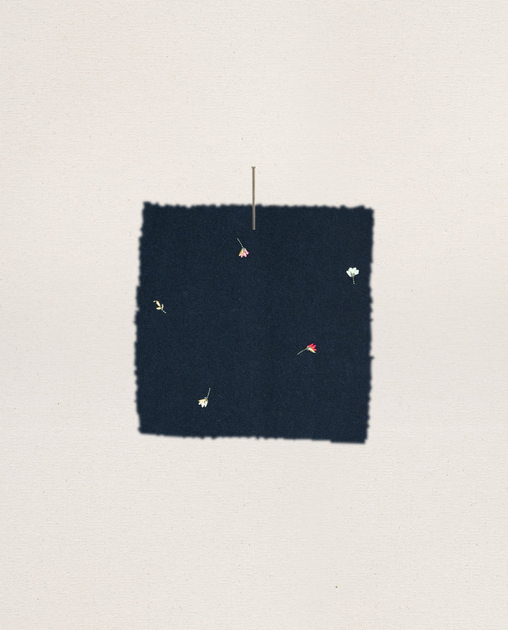Dark blue square patch with floral embroidery on a light gray background