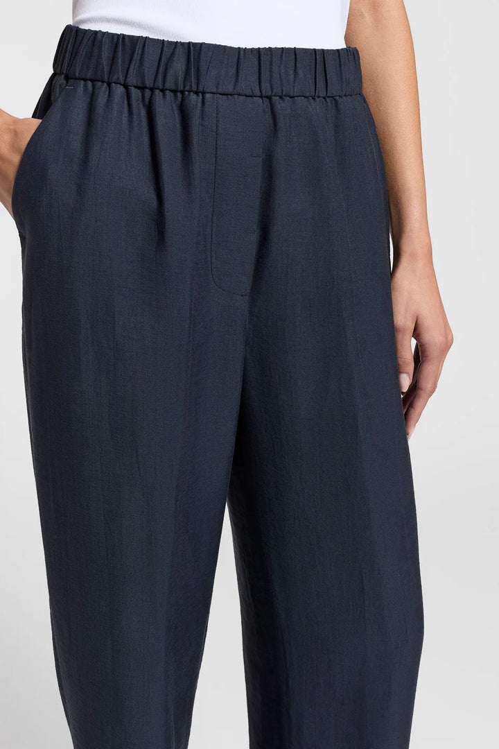Dark gray pants worn by a person on a white background