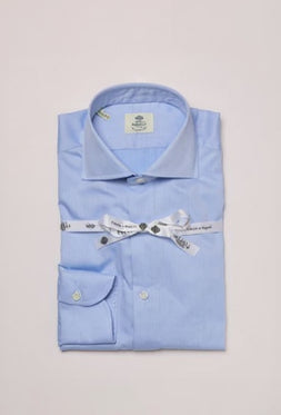 Folded light blue dress shirt with a label on a light gray background