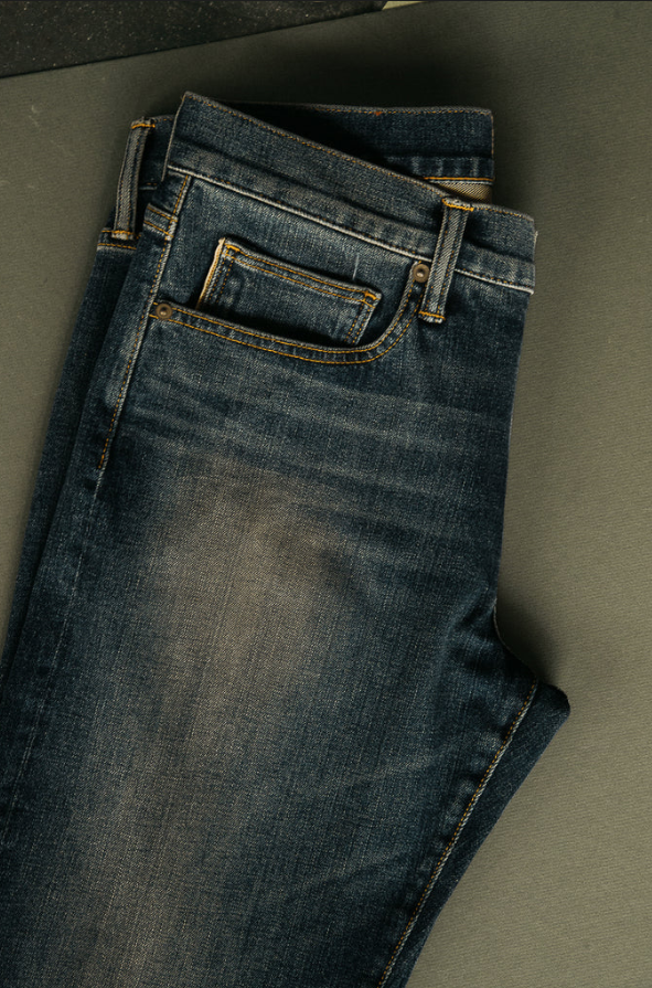 Folded pair of blue jeans on a gray surface