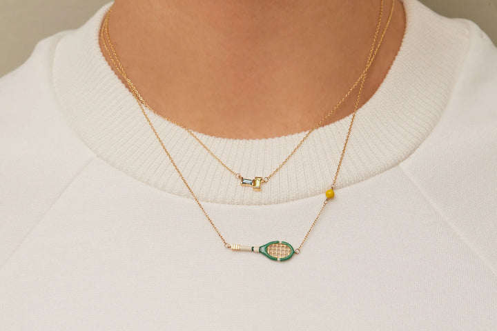 Gold necklace with a green pendant on a white sweater