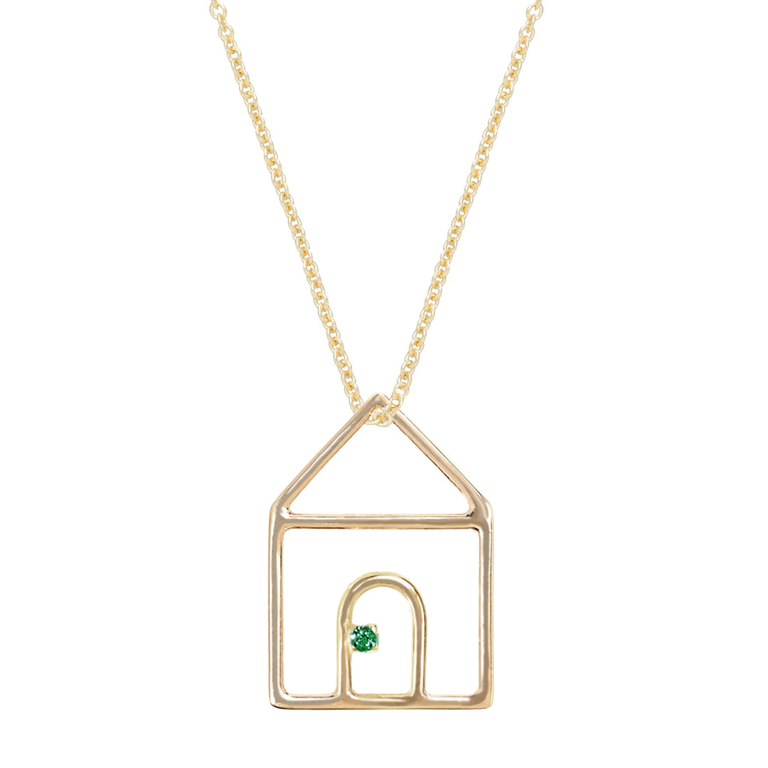 Gold necklace with a house-shaped pendant featuring a green gemstone on a white background