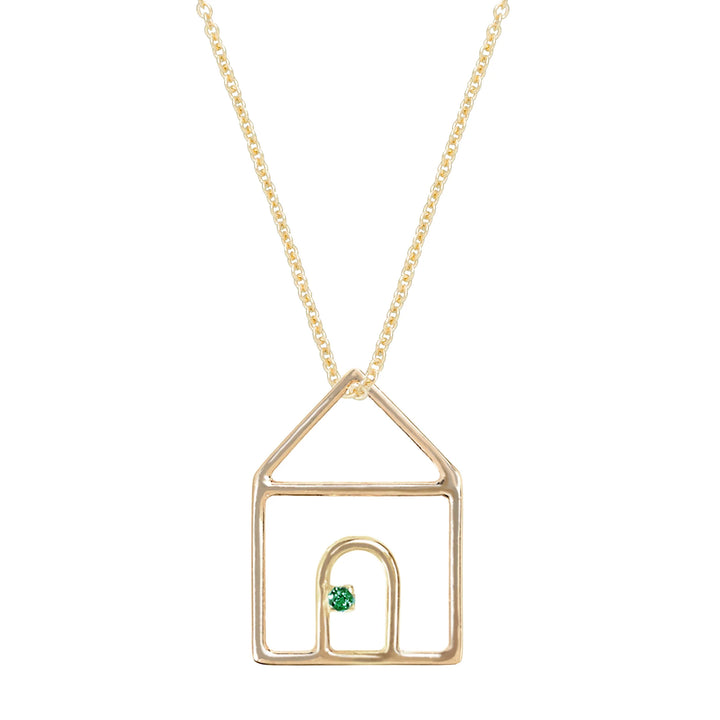 Gold necklace with a house-shaped pendant featuring a green gemstone on a white background