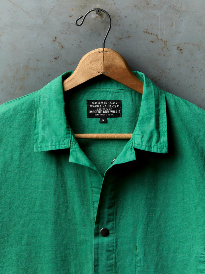 Green shirt on a wooden hanger against a textured gray background