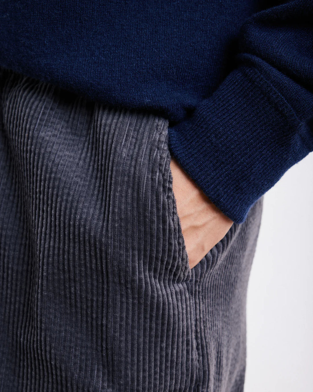 Navy sweater and gray corduroy pants on a white background