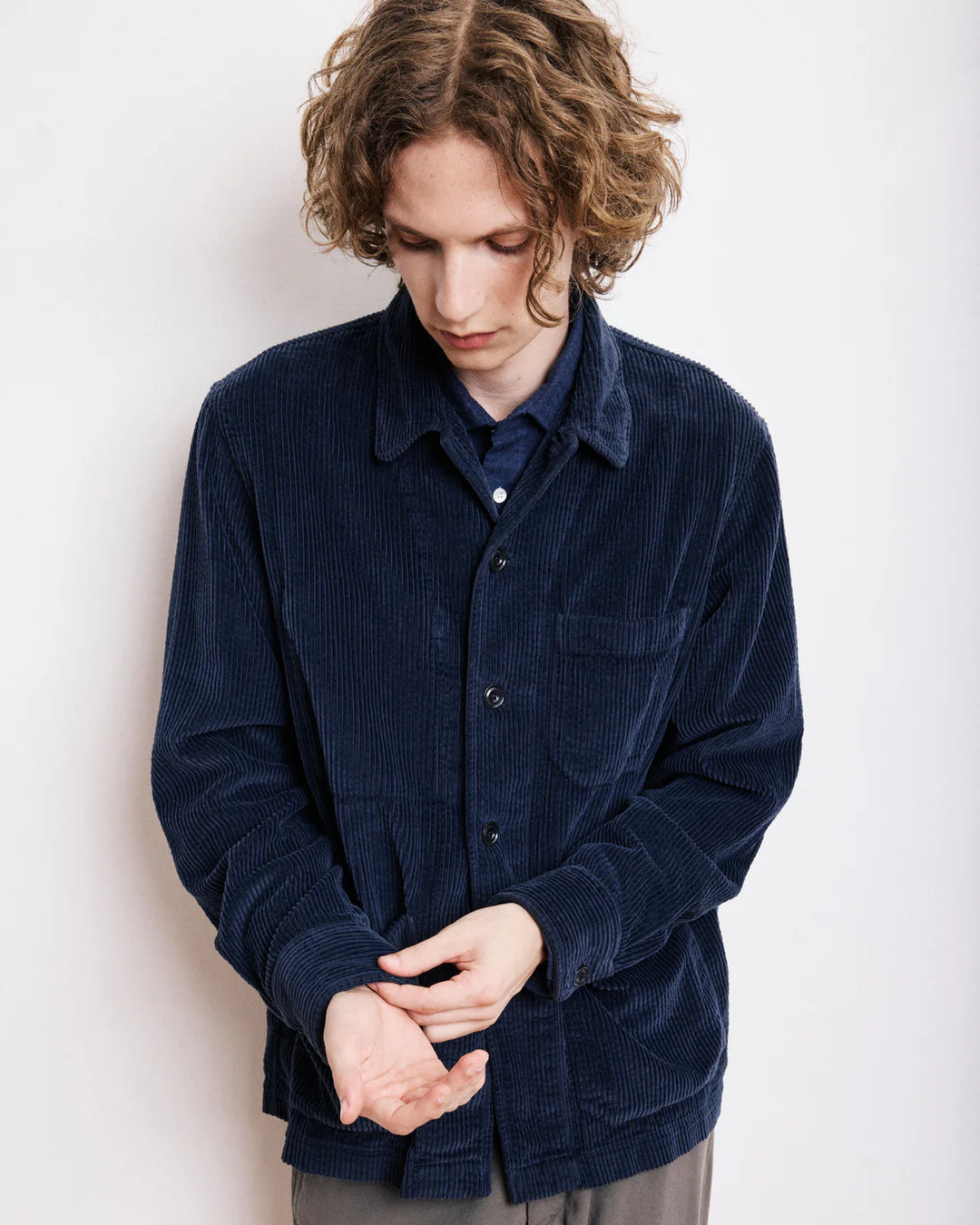 Man wearing a navy blue corduroy shirt against a white background