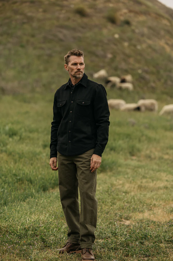 Man standing in a field with sheep in the background