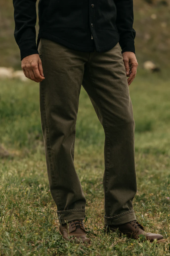 Person wearing dark pants and a black shirt standing in a grassy field