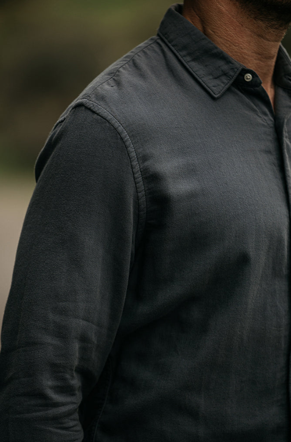 Close-up of a person wearing a dark gray shirt with a blurred background