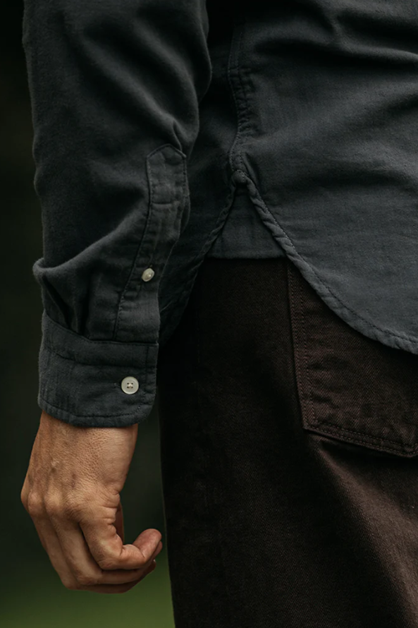 Close-up of a person wearing a dark shirt with rolled-up sleeves and a dark jacket.