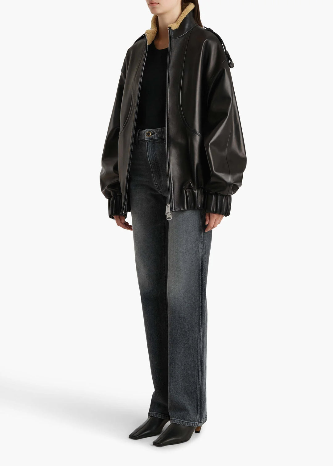 Person wearing a black leather jacket and jeans on a white background