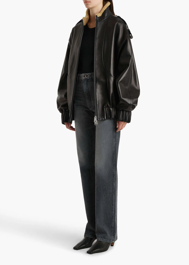 Person wearing a black leather jacket and jeans on a white background