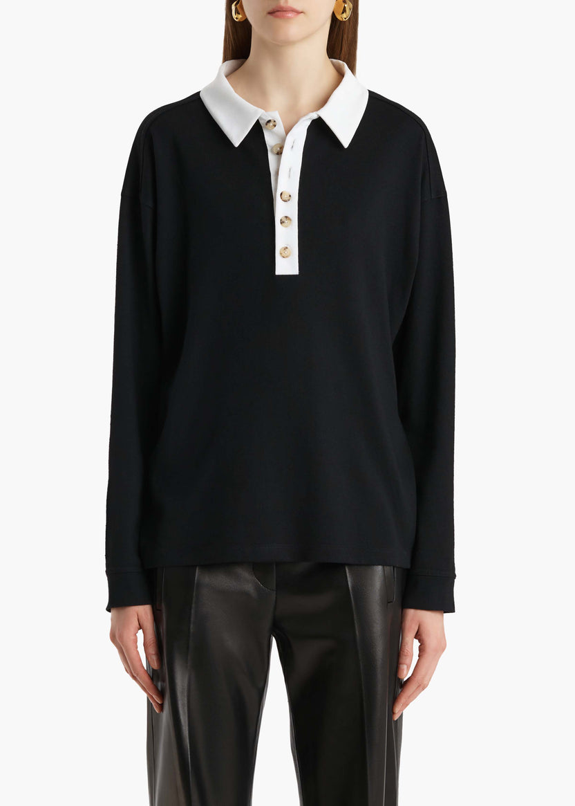 Black long-sleeve shirt with white collar worn by a person on a white background