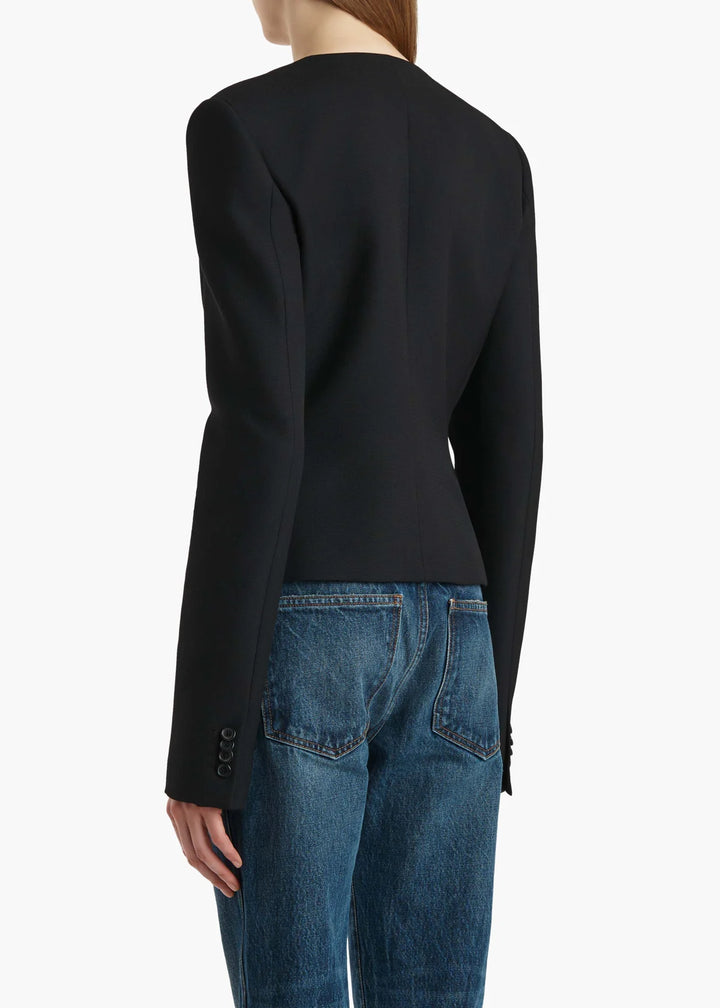 Person wearing a black long-sleeve top and blue jeans on a white background