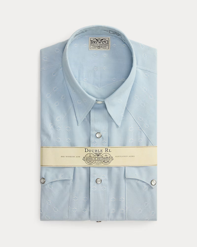 Light blue dress shirt with collar and buttons, displayed in packaging on a white background