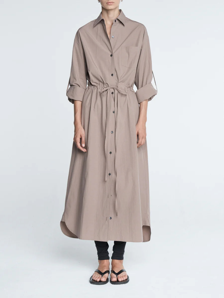 Long beige dress worn by a person on a white background