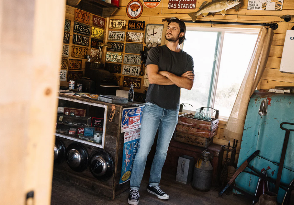 Man standing in a room with vintage decor, including license plates and a TV.