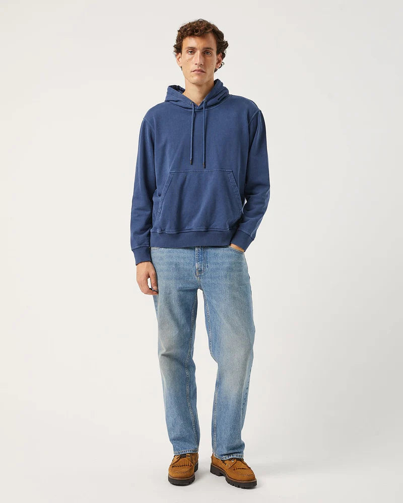 Man wearing a blue hoodie and light blue jeans on a white background