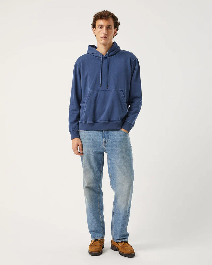 Man wearing a blue hoodie and light blue jeans on a white background