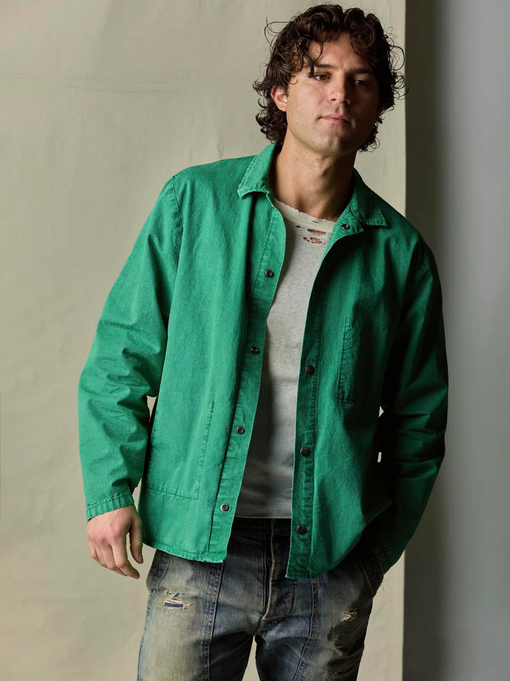 Man wearing a green jacket over a gray shirt against a neutral background