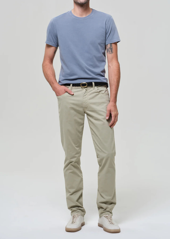Man wearing a light blue t-shirt and beige pants on a white background