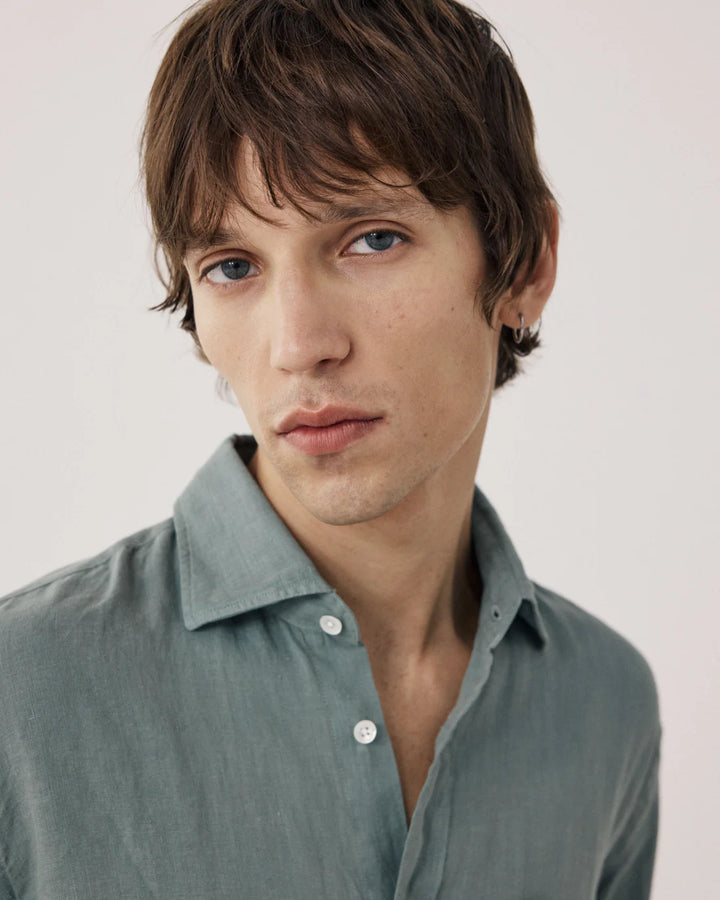 Man wearing a light green shirt against a plain background