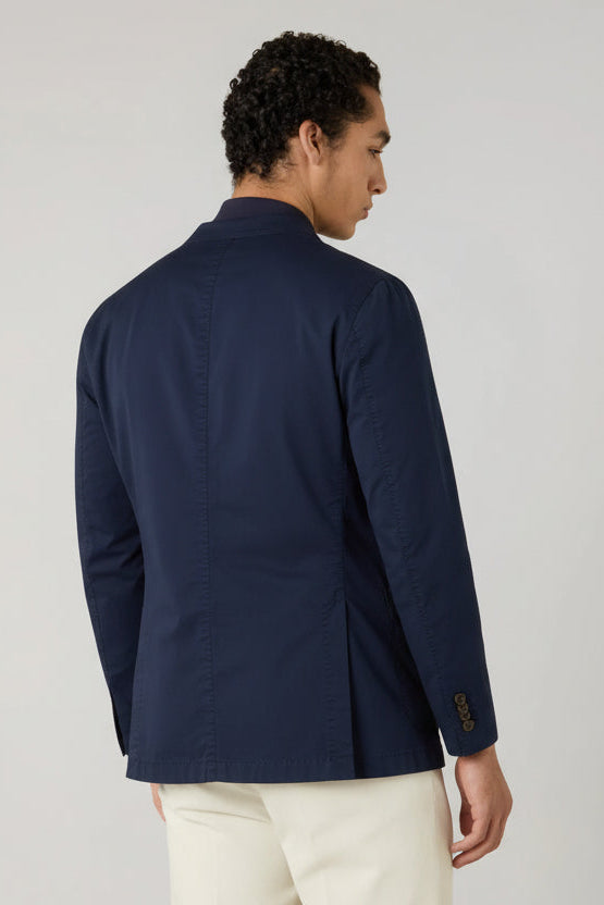 Man wearing a navy blazer and white pants on a light gray background