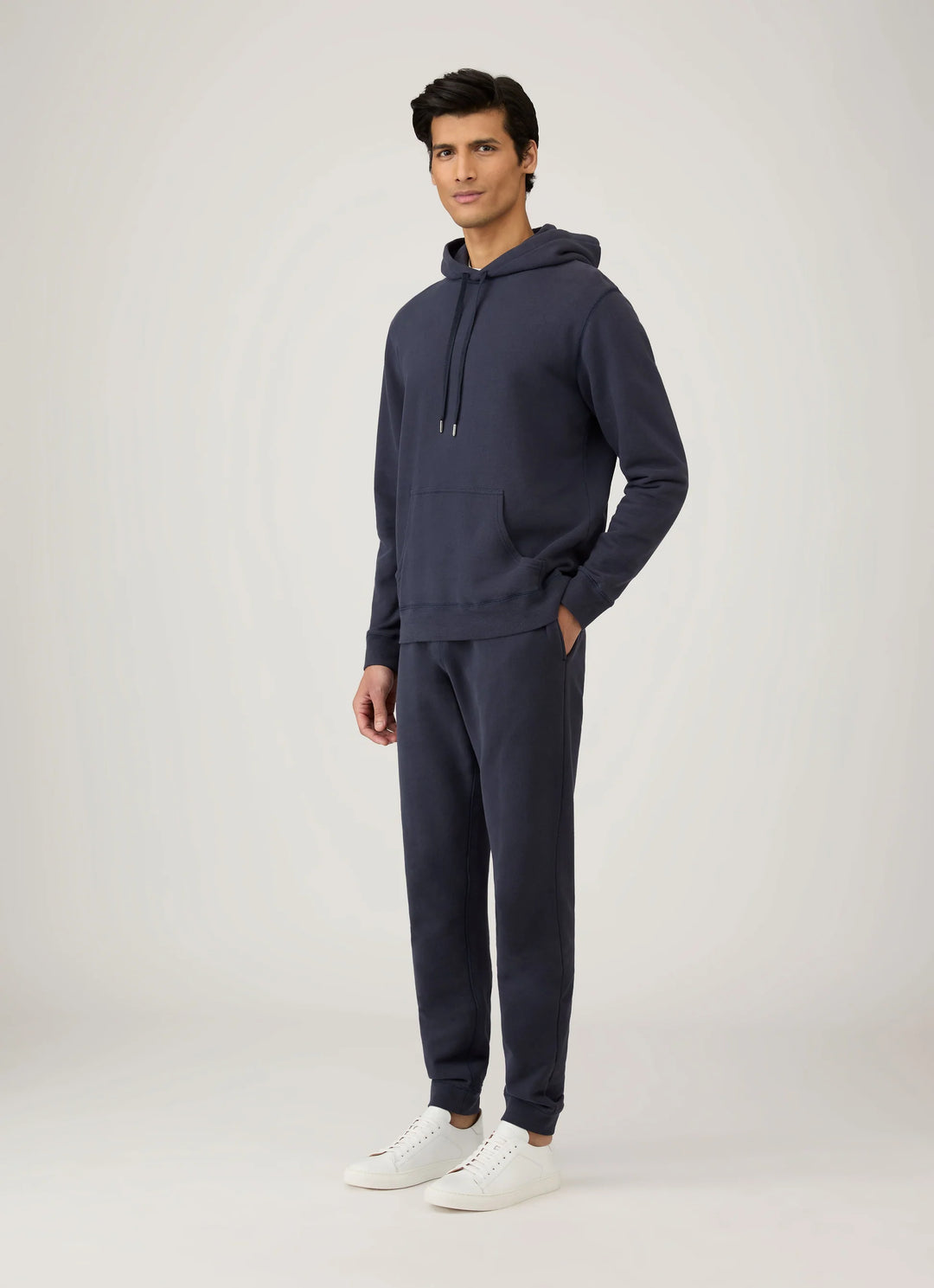Man wearing a navy hoodie and jogger set on a white background