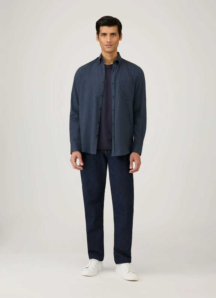 Man wearing a navy jacket, shirt, and pants with white shoes on a light gray background