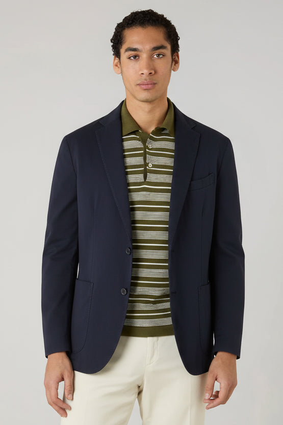 Man wearing an olive green blazer over a striped shirt on a plain background