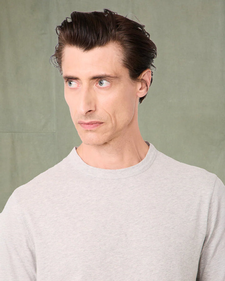 Man with styled hair wearing a light gray sweater against a plain background