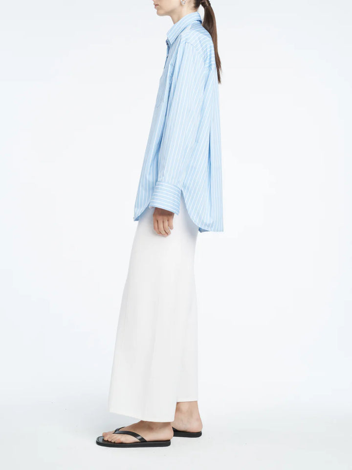 Person wearing a light blue striped shirt and white pants on a white background