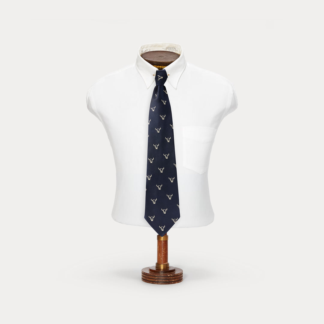 Navy blue tie with white pattern on a mannequin torso against a white background
