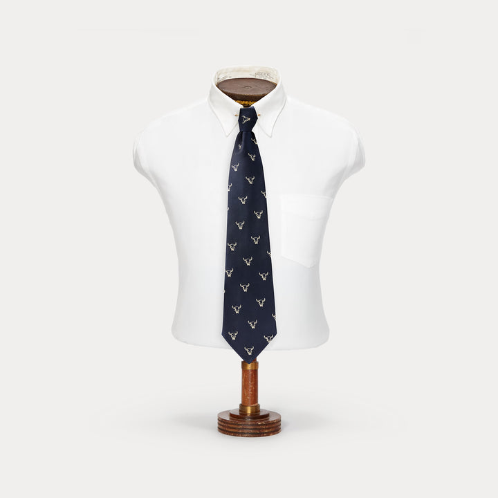 Navy blue tie with white pattern on a mannequin torso against a white background