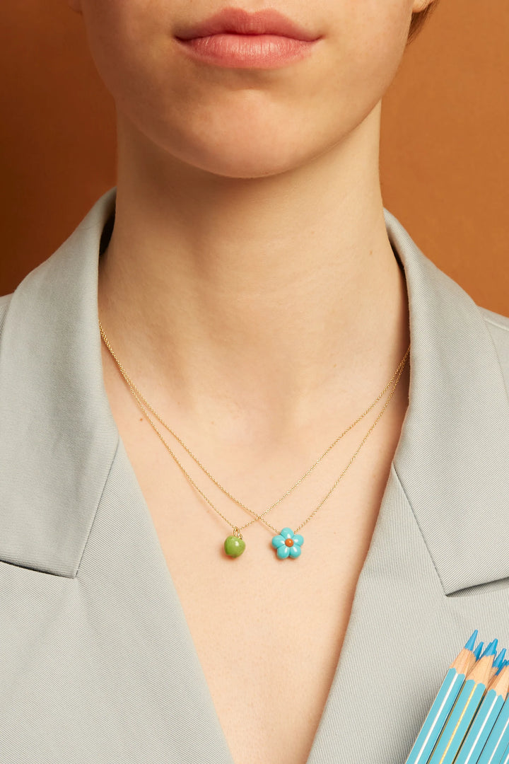 Necklace with a green bead and turquoise flower pendant on a person wearing a light gray blazer.
