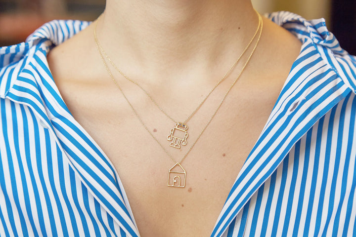 Necklace with a pendant on a person wearing a blue and white striped shirt.