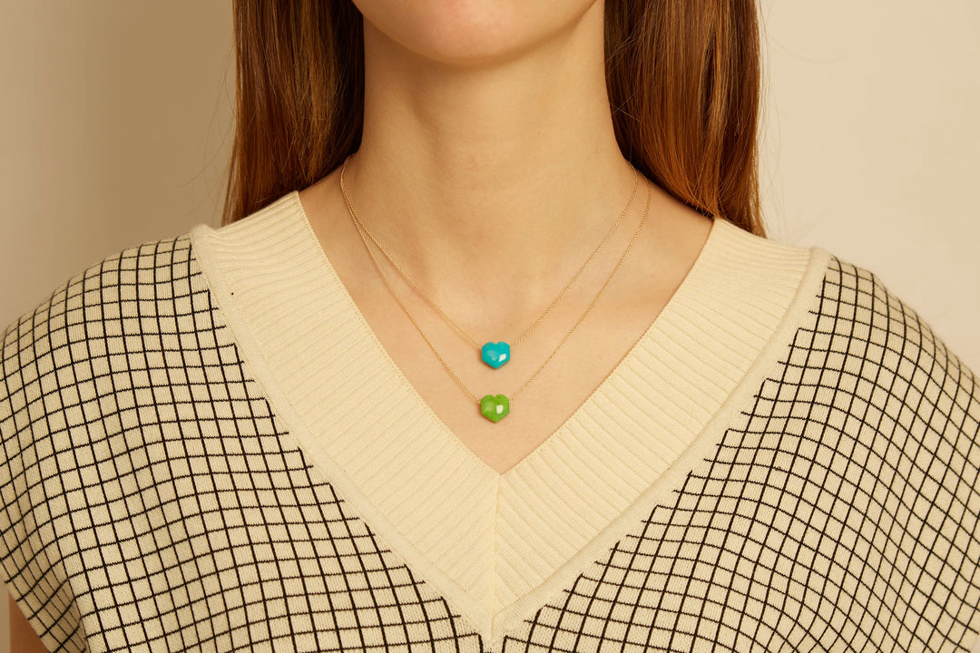 Necklace with turquoise and green beads worn by a person in a checkered shirt.